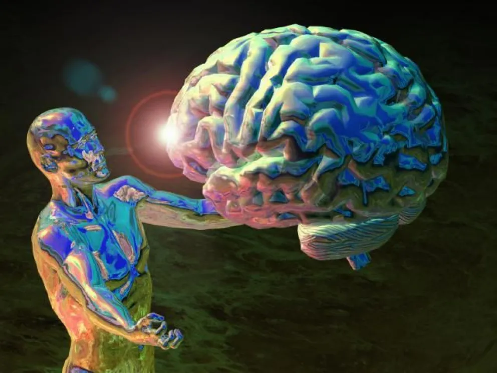 La imagen muestra una figura humanoide, de aspecto metálico y brillante con tonos azules, verdes y dorados, sosteniendo un cerebro humano de gran tamaño. El cerebro, también con una superficie iridiscente en tonos azules y verdes, parece emitir un resplandor en el punto donde se une a la mano de la figura. El fondo es oscuro y difuso, con algunas tonalidades verdosas, creando un ambiente de misterio o profundidad espacial. La pose de la figura y la forma en que sostiene el cerebro sugieren una interacción profunda o una presentación solemne del órgano.
